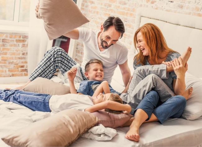 Famille qui s'amuse sur un lit.